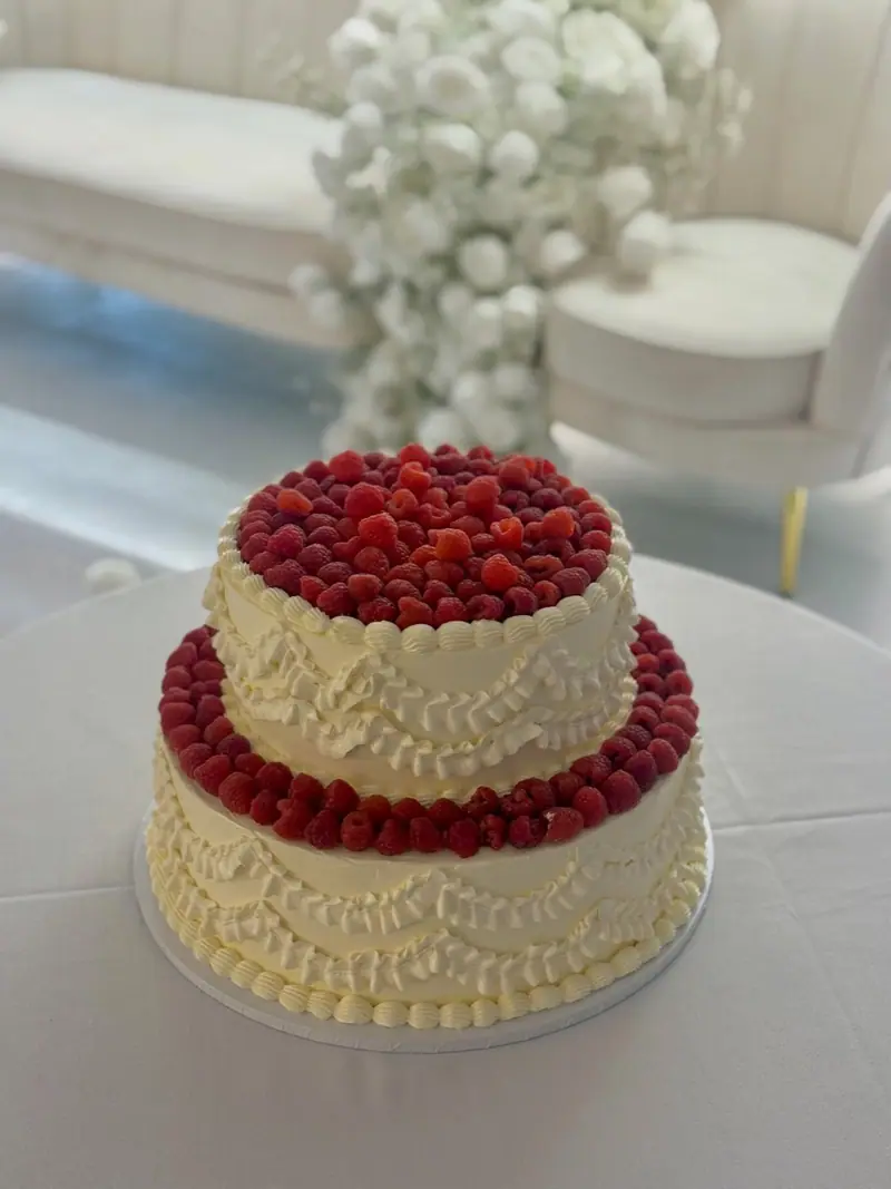 Two-tier vintage wedding cake with hand-piped ruffles and fresh raspberries at the Chigwell Marquees